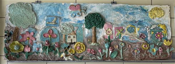 A ceramic and cement wall sculpture created by sixth-graders